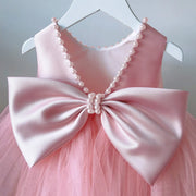 Pink dress with a large bow and pearl details on a hanger