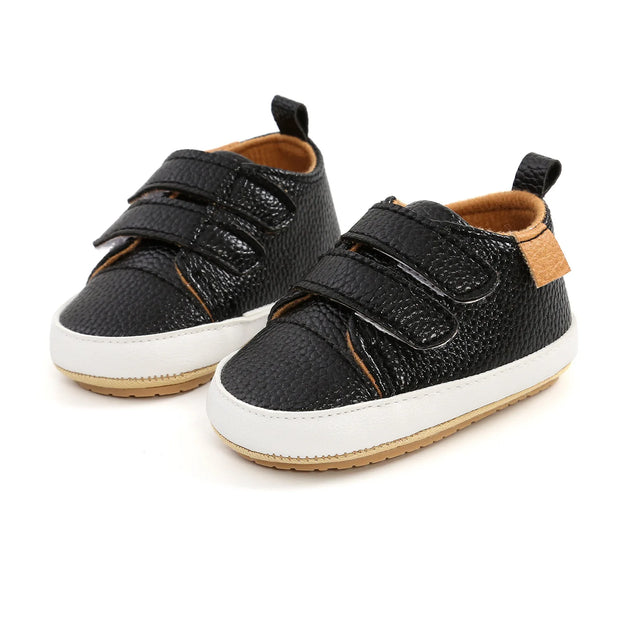 Black children's shoes with velcro straps on a white background