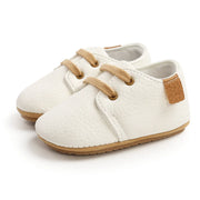 White baby shoes with brown accents on a white background