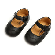 Pair of black baby shoes with a strap on a white background