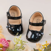 Black patent leather shoes with bows on a light background with flowers.