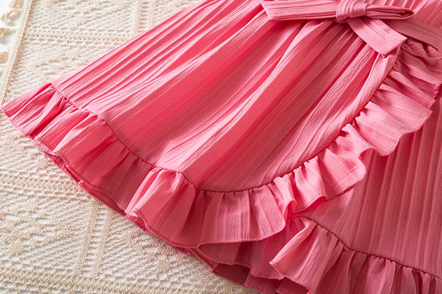Close-up of a pink ruffled skirt on a textured surface
