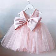 Pink dress with a large bow on a hanger against a light background