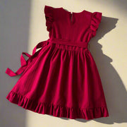 Red dress with ruffled sleeves and bottom on a textured surface with decorative elements.