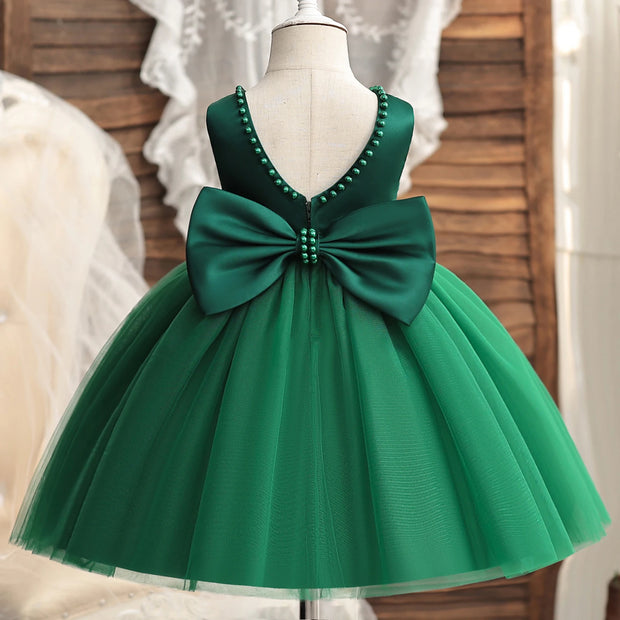 Green dress with a large bow on a mannequin against a neutral background