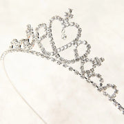 Silver tiara with rhinestones on a light pink background