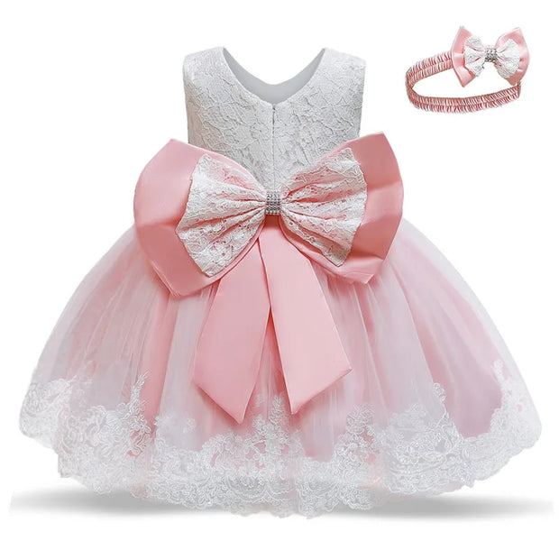 Pink and white lace dress with a large bow and matching headband on a white background