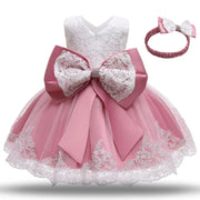 Pink and white lace dress with a large bow and matching headband on a white background