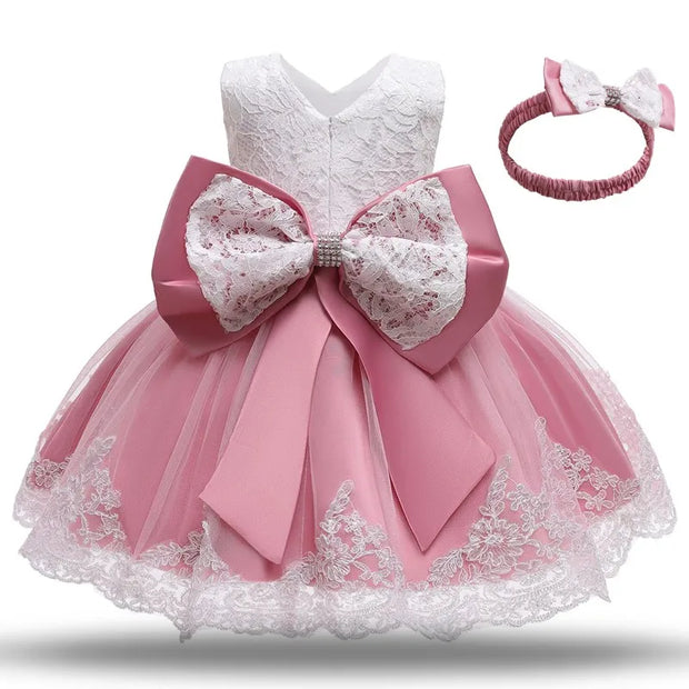 Pink and white lace dress with a large bow and matching headband on a white background