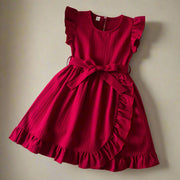 Red dress with ruffled sleeves and bottom on a textured surface with decorative items.