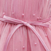 Close-up of a pink dress with a belt and pearl embellishments