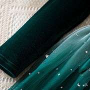 Green velvet fabric and green tulle fabric with star and moon patterns on a textured surface.