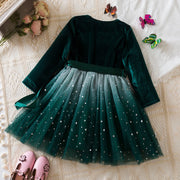 Green velvet dress with tulle skirt on a textured surface with decorative elements.