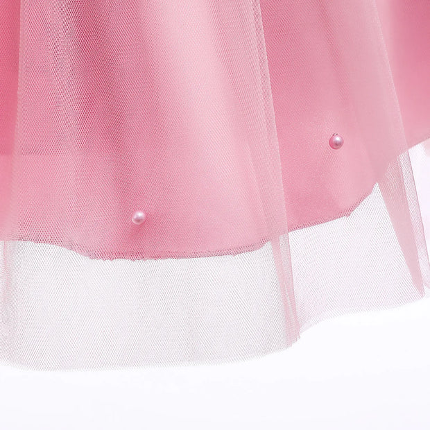 Close-up of a pink and white tulle skirt with pearl buttons on a light background