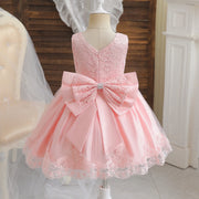 Pink lace dress with a large bow on a mannequin against a neutral background