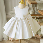 White dress with a large bow on a mannequin against a blurred indoor background