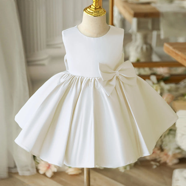 White dress with a large bow on a mannequin against a blurred indoor background