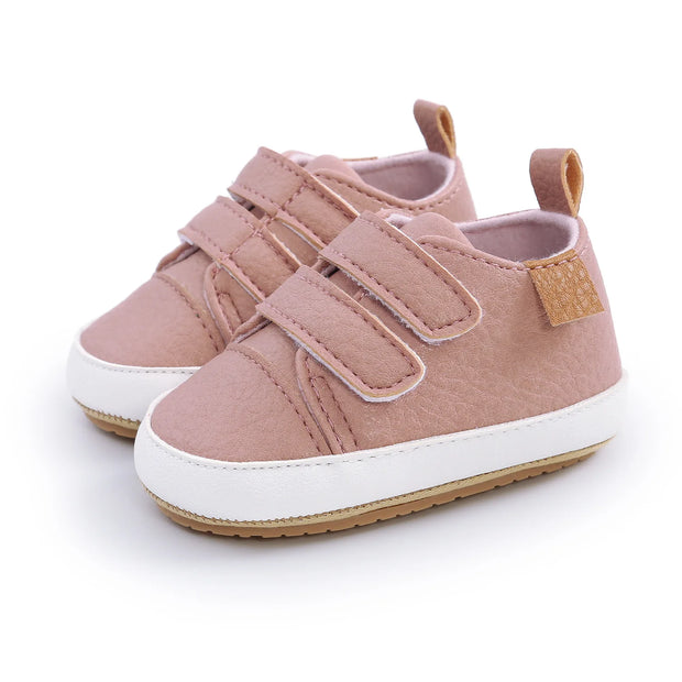Pair of pink children's shoes with velcro straps on a white background
