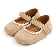 Pair of beige baby shoes with a strap on a white background