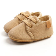 Pair of beige baby shoes with soft sole on a white background