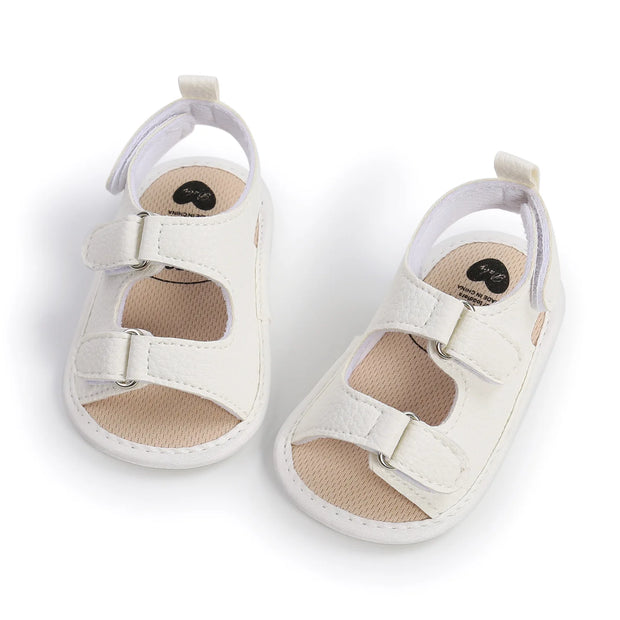 White baby sandals with beige soles on a white background