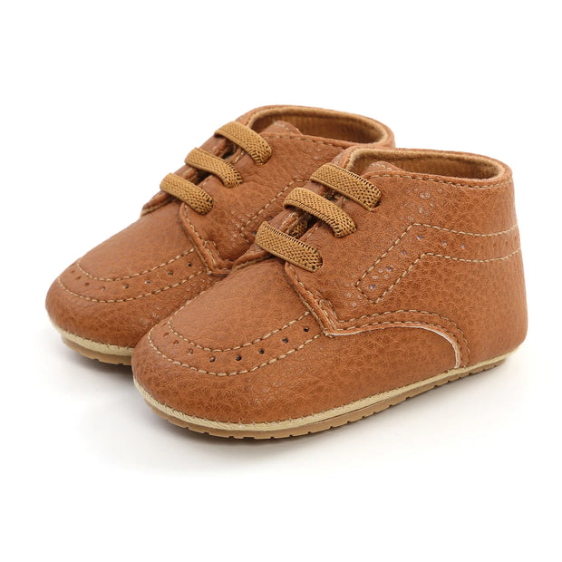 Pair of brown baby shoes with laces on a white background