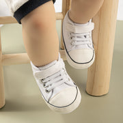Children's white sneakers with velcro straps on a light green background