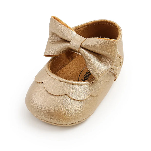 Gold baby shoe with a bow on a white background
