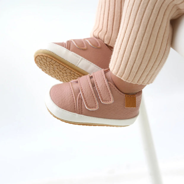Pink baby shoes with velcro straps on a white background