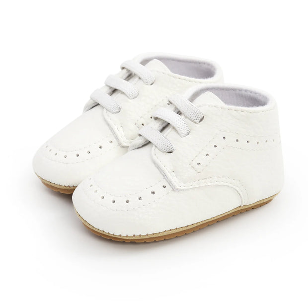 White baby shoes with brown soles on a white background