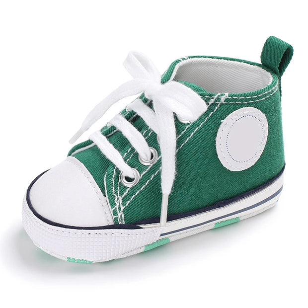 Green baby shoe with white laces on a white background