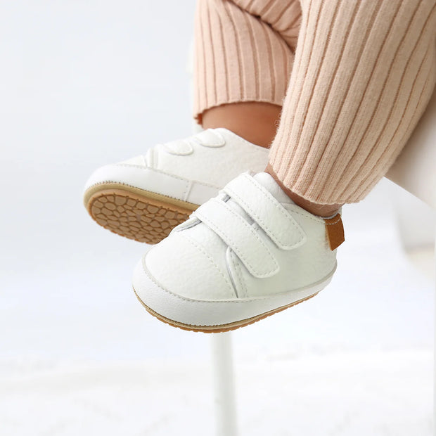 White baby shoes with velcro straps on a white background