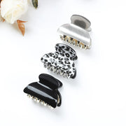 Three hair clamps in black, white, and silver on a white background