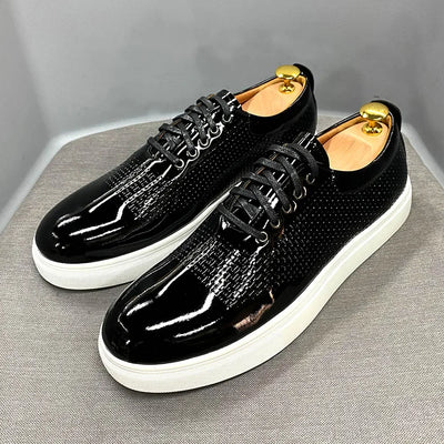 Black patent leather shoes with white soles on a gray background