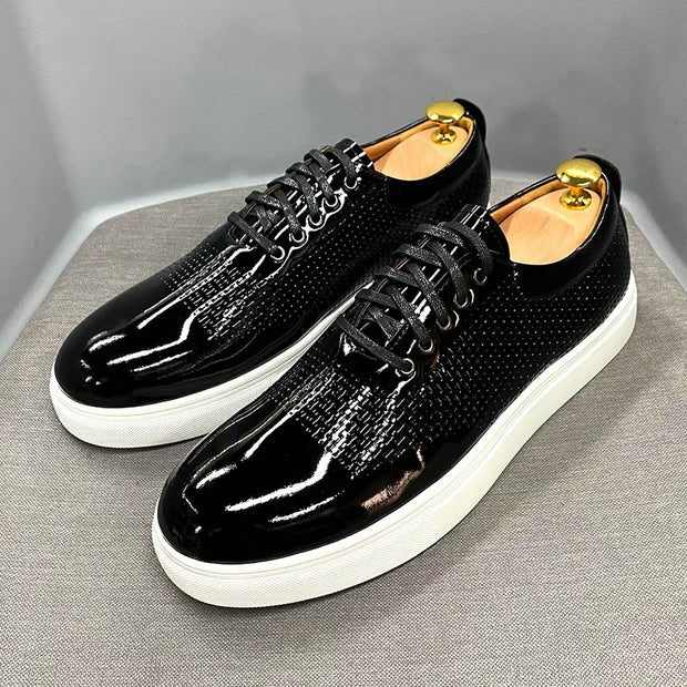 Black patent leather shoes with white soles on a gray background