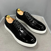 Black patent leather shoes with white soles on a gray surface