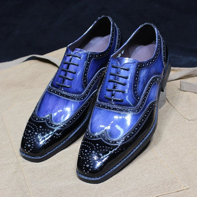 Pair of blue and black shiny dress shoes on a beige surface with a dark background