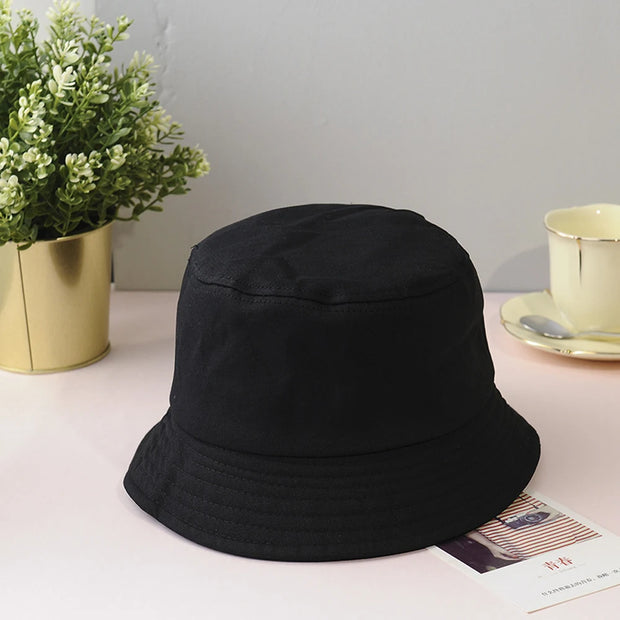 Black bucket hat on a surface with a plant and teacup in the background