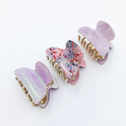 Three butterfly-shaped hair clips with floral design on a white background