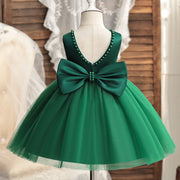 Green dress with a large bow on a mannequin against a neutral background