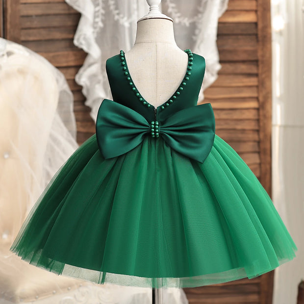 Green dress with a large bow on a mannequin against a neutral background