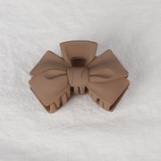 Brown bow-shaped hair clip on a white textured background