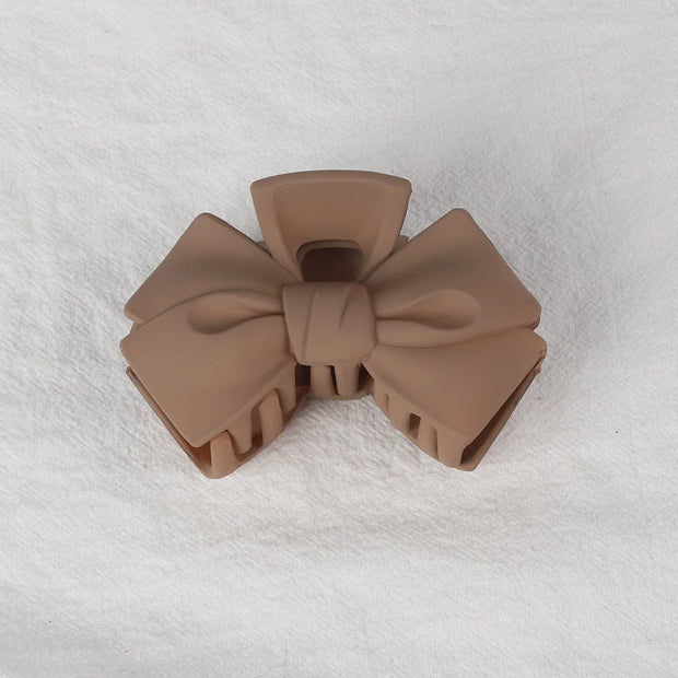 Brown bow-shaped hair clip on a white textured background