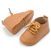 Pair of brown children's shoes with laces on a white background