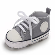 Gray baby shoe with white laces on a white background