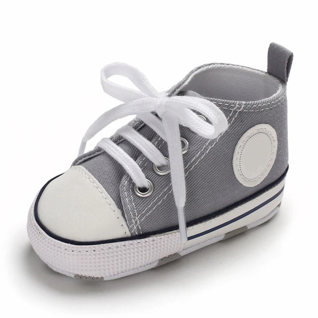 Gray baby shoe with white laces on a white background
