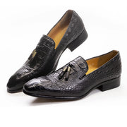 Black crocodile-patterned loafers with tassels on a white background
