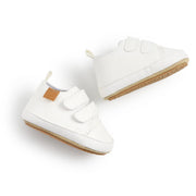 White baby shoes with velcro straps on a light gray background