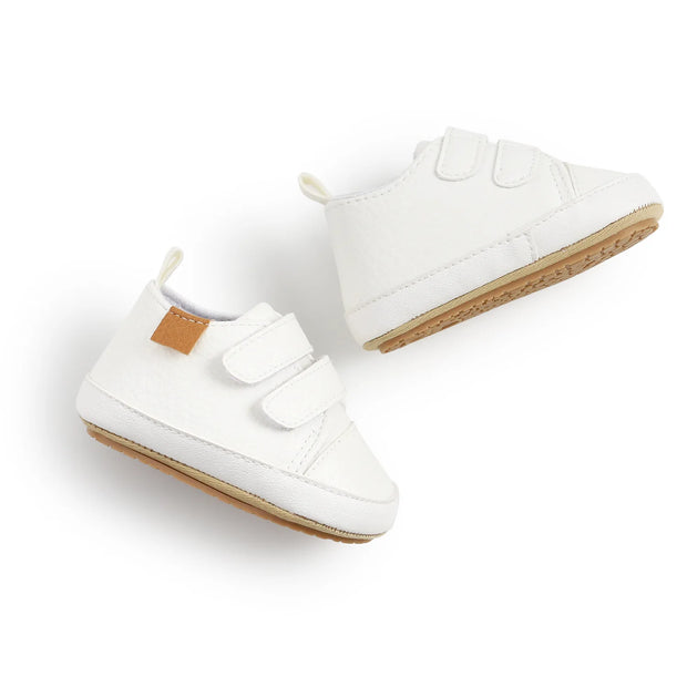 White baby shoes with velcro straps on a light gray background