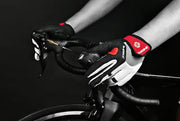Person wearing black and white cycling gloves with red accents on a bike.